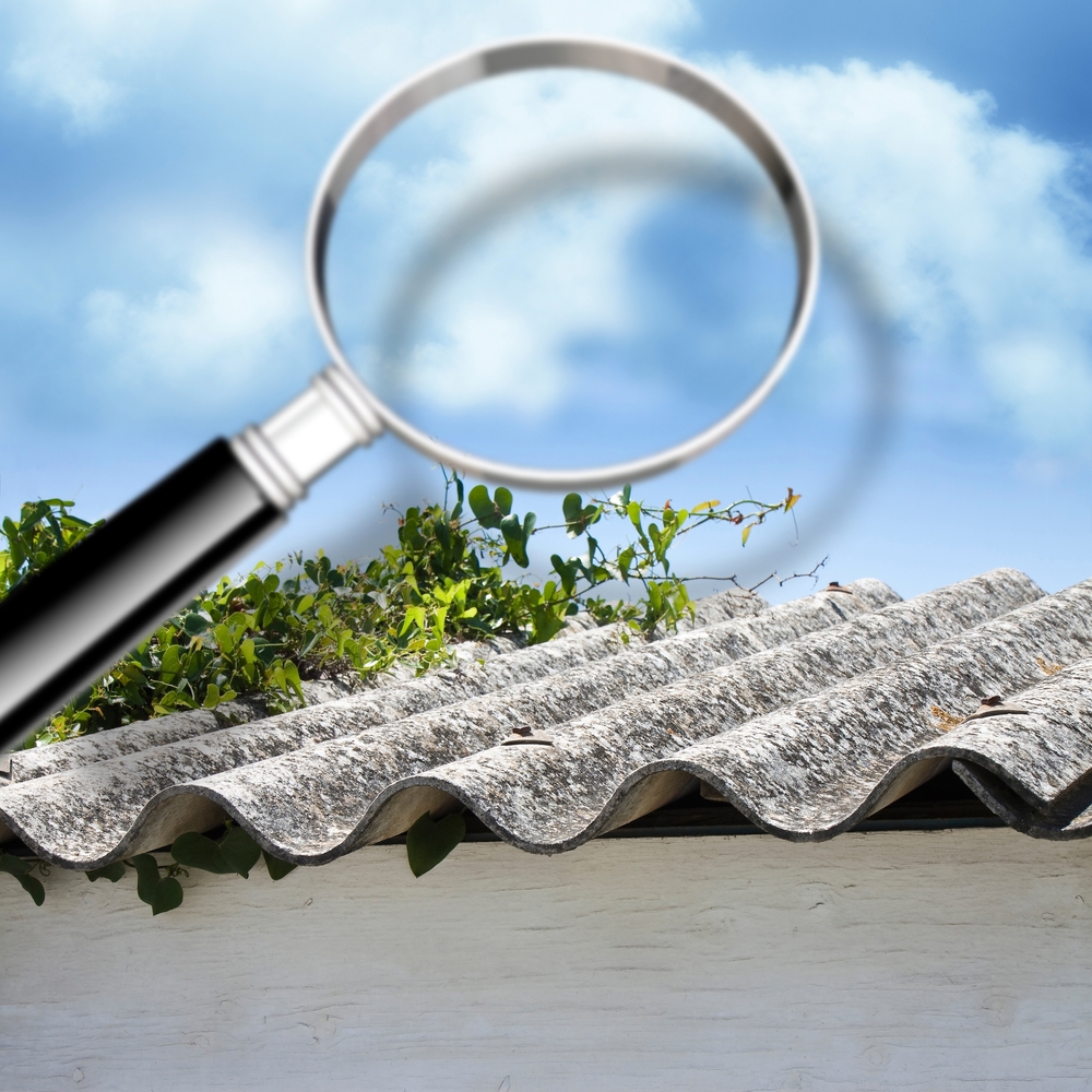 Magnifying glass inspecting asbestos roof for damage or contamination